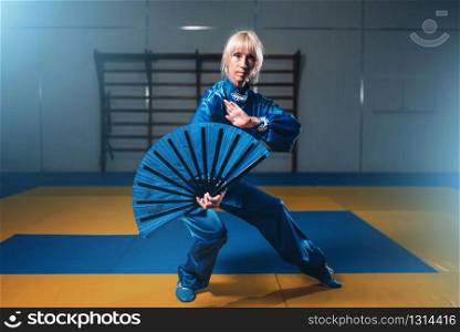 Female wushu master with fan, martial arts. Woman in blue cloth on fight training. Female wushu master with fan, martial arts