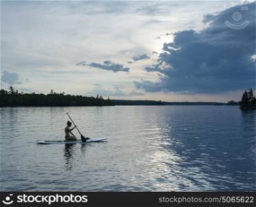 Female youth paddleboarding in the lake, Lake of The Woods, Ontario, Canada
