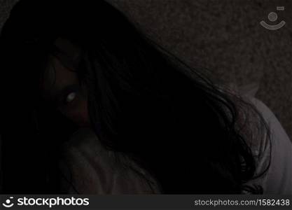 Female zombie in blood. Asian Woman ghost with blood. Horror creepy scary fear she sitting in a dark house. Hair covering the face, Halloween festival concept