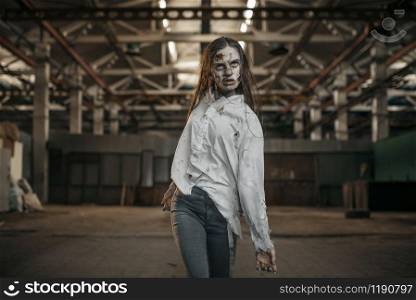 Female zombie walking in abandoned factory, scary place. Horror in city, creepy crawlies attack, doomsday apocalypse, bloody evil monsters