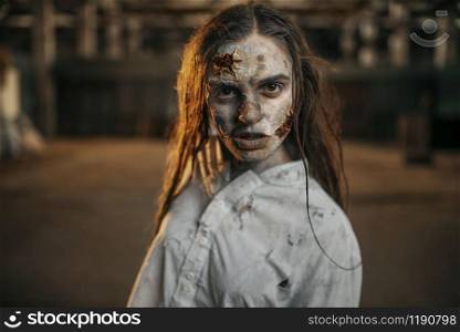 Female zombie walking in abandoned factory, scary place. Horror in city, creepy crawlies attack, doomsday apocalypse, bloody evil monster. Female zombie walking in abandoned factory, horror