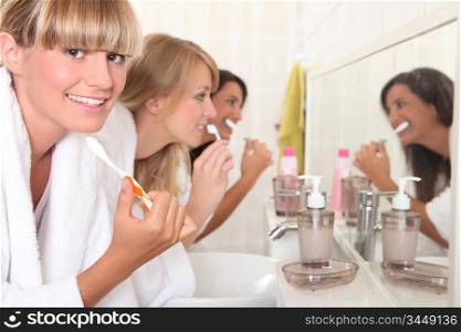 Females roommates brushing teeth