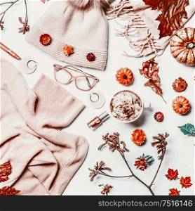 Feminine autumn flat lay with knitted sweater, hat, reading glasses, cup of cappuccino, scarf, make up cosmetics, pumpkins and dries flowers. Top view. Blog layout. Insta style. Fashion and beauty