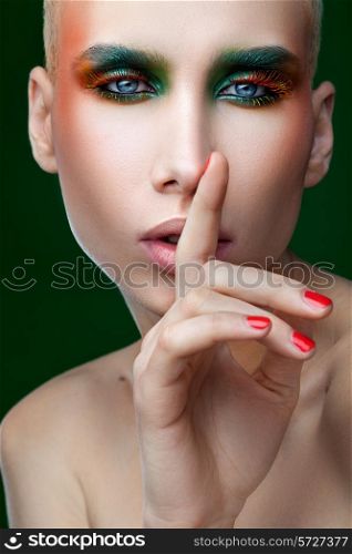 Feminine man with makeup on green background