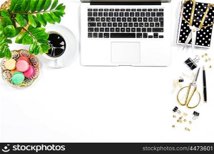 Feminine workplace. Coffee, macaroon cookies, office supplies, laptop computer and green plant on white table background. Top view. Flat lay
