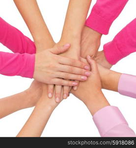 feminism, women power and breast cancer awareness concept - close up of women hands on top of each other over white background