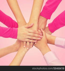 feminism, women power and breast cancer awareness concept - close up of women hands on top of each other over white background