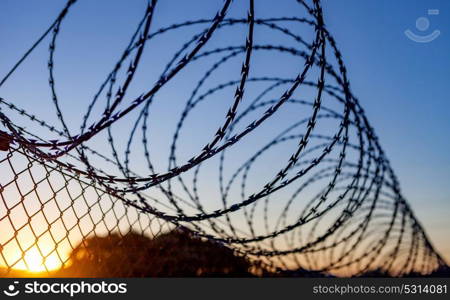 Fence with a barbed wire under a blue sky