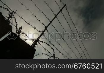 Fence with barbed wire surrounding secured property. Pan shot