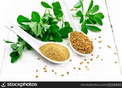 Fenugreek seeds and ground spice in two spoons and on a table with green leaves on white wooden board background