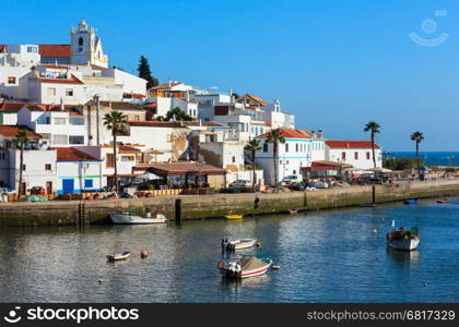 Ferragudo fishing village evening summer view with boats on water (near Marina Portimao, Lagoa, Algarve, Portugal). Peoples are unrecognizable.