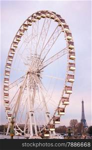 Ferries wheel in Paris at twilight. Eiffel Tower on the background.