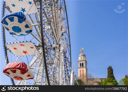 Ferris Wheel at the county fair with the sky in the background and a bell tower