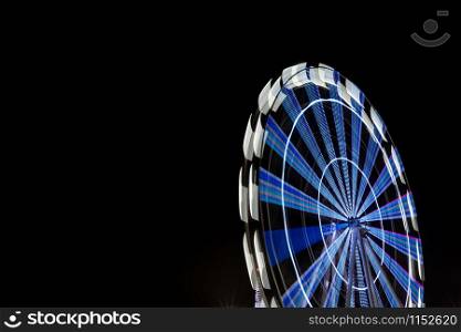 Ferris wheel illuminated at night with long exposure and isolated on black sky. Long exposure of ferris wheel illuminated at night