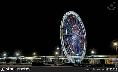 Ferris wheel illuminated at night with long exposure and isolated on black sky. Long exposure of ferris wheel illuminated at night with copy space