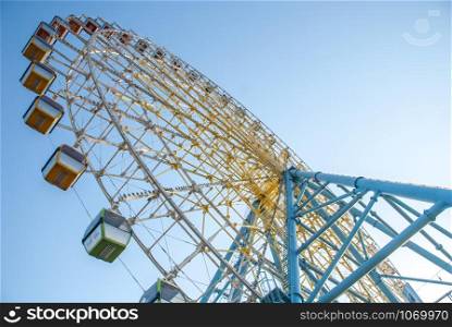 Ferris wheel in an amusements park. Yellow and blue ferris wheel. Joy wheel.