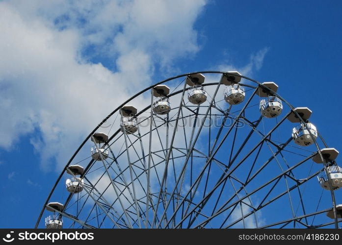 Ferris wheel on half, blue sky and white clouds