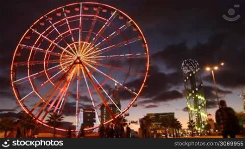 Ferris wheel rotates in the middle of the city at night