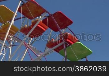 Ferris wheel with multicolored cabins in amusement park