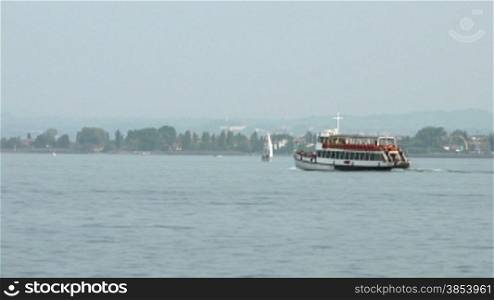 Ferry boat with tourists traveling between Desenzano and Sirmione, Lake Garda, Italy