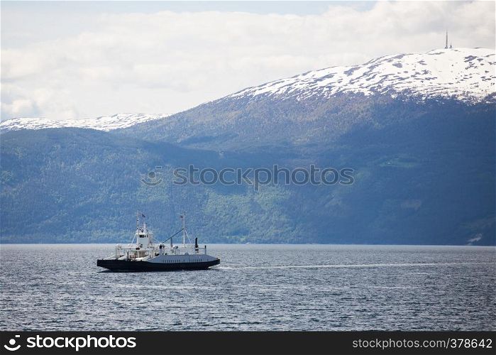 ferry crossing a norwegian fjord with mountains at the background