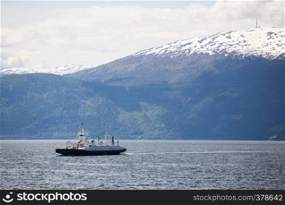 ferry crossing a norwegian fjord with mountains at the background