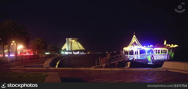 Ferrymen (faces blurred by time exposure) wait for customers on the Corniche during a busy evening in April, 2009, in Doha, Qatar. Medium format film photograph.