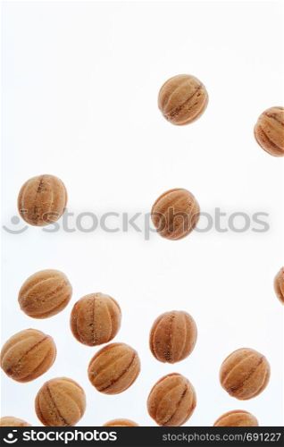 Feshly baked homemade cakes in a shape of walnuts filled milk cream on a white background with copy space.. Falling homemade cookies walnuts on a white background.