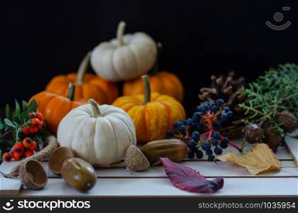 Festive autumn decor from pumpkins, leaves, pinecone and acorn on a wooden background. Concept of Thanksgiving day or Halloween.