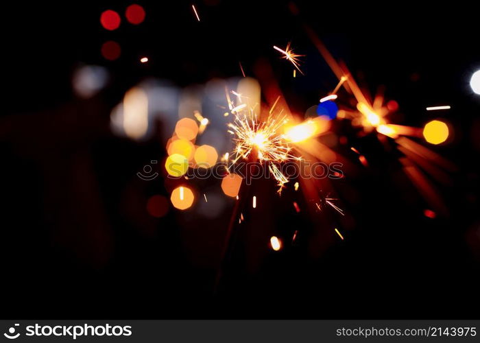 Festive background, bengal light on the dark background, New Year with sparklers sparks on a festive background. selective focus. Festive background, bengal light on the dark background, New Year with sparklers sparks on a festive background. selective focus.