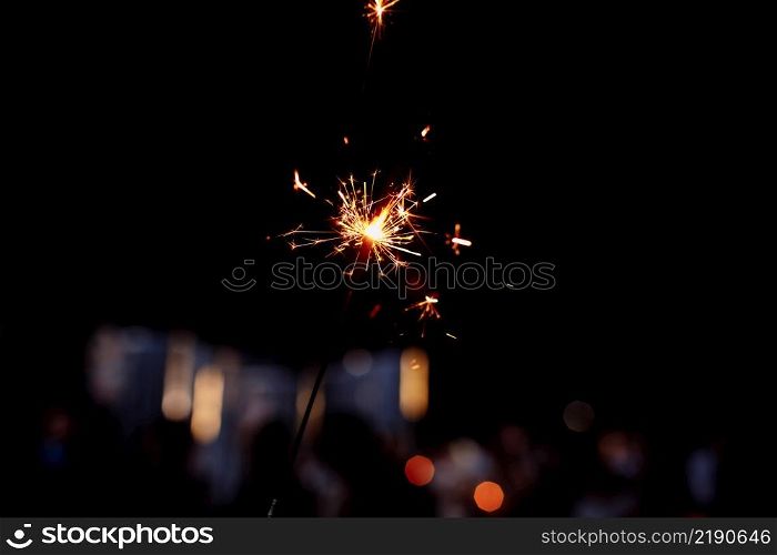 Festive background, bengal light on the dark background, New Year with sparklers sparks on a black background. selective focus. Festive background, bengal light on the dark background, New Year with sparklers sparks on a black background. selective focus.