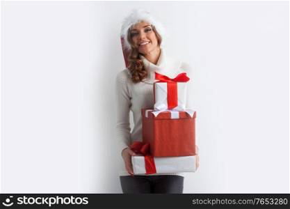 Festive blonde woman in Santa hat holding pile of Christmas gifts on white background. Woman holding pile of gifts