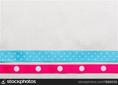 Festive celebration party frame. Polka dot blue and pink satin ribbon on white cloth background