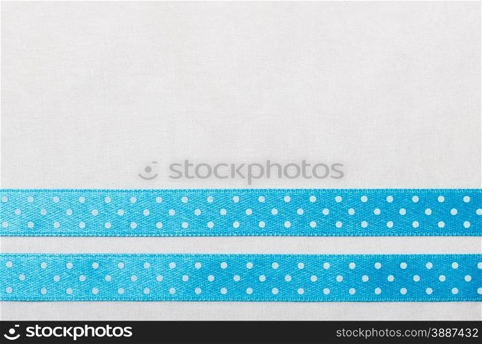 Festive celebration party frame. Polka dot blue satin ribbon on white cloth background
