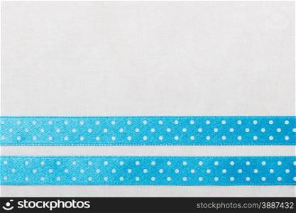 Festive celebration party frame. Polka dot blue satin ribbon on white cloth background