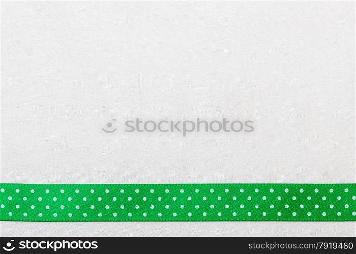 Festive celebration party frame. Polka dot green satin ribbon on white cloth background