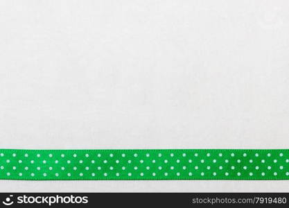 Festive celebration party frame. Polka dot green satin ribbon on white cloth background