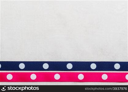 Festive celebration party frame. Polka dot navy blue and pink satin ribbon on white cloth background