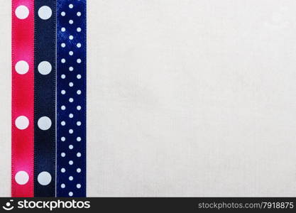 Festive celebration party frame. Polka dot navy blue and pink satin ribbon on white cloth background