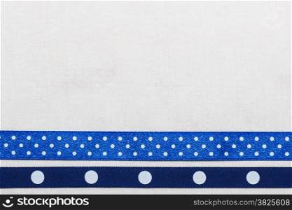 Festive celebration party frame. Polka dot navy blue satin ribbon on white cloth background