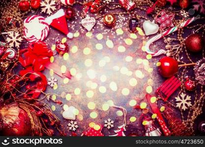 Festive Christmas background with various red decorations and candy with bokeh light, top view, frame