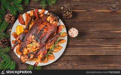 Festive Christmas duck baked with apples and quince and spices on dark vintage table. Festive dinner for Christmas or New Year. Cooking recipe, layout on wooden background decorated with fir branches