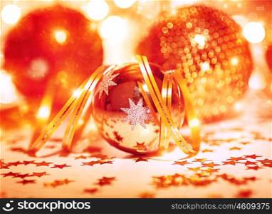 Festive Christmas still life, beautiful golden shiny decorative balls with ribbon and little stars on the table, traditional winter holidays decor