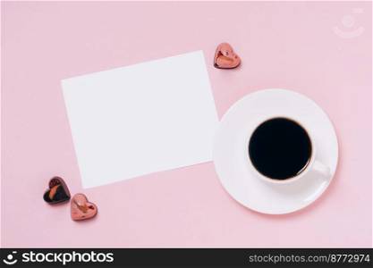 Festive composition for Valentine’s Day. Chocolate candies hearts in a festive box, a cup of coffee, a blank sheet of paper on a pink background. Flat layout copy space, place for your text. Chocolate candies hearts festive box, cup of coffee, blank sheet of paper pink background. Concept Valentine’s Day