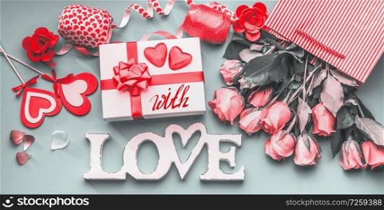 Festive composition of love for Valentines day made with gift box and red bow, shopping bag and roses, hearts and party accessories. With Love message. Flat lay, View from above