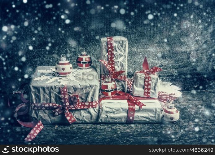 Festive gifts and presents decorating with cut paper snowflakes and red ribbons on dark rustic background. Vintage Style toned