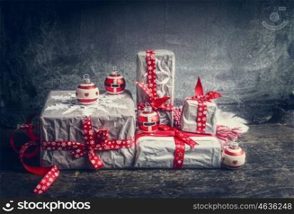 Festive gifts and presents decorating with handmade cut paper snowflakes and red ribbons on dark rustic background