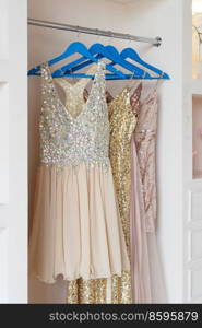 festive golden dresses hanging in closet. wardrobe with clothes