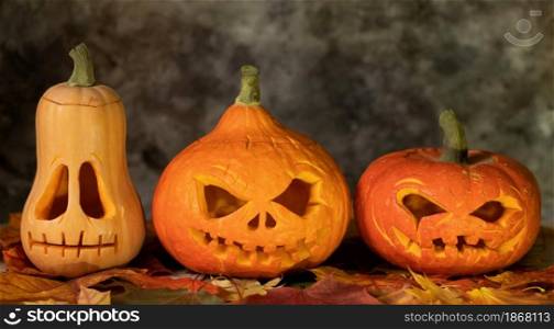 Festive halloween pumpkins on leaves on a dark background. Festive scary halloween pumpkins on leaves on a dark background