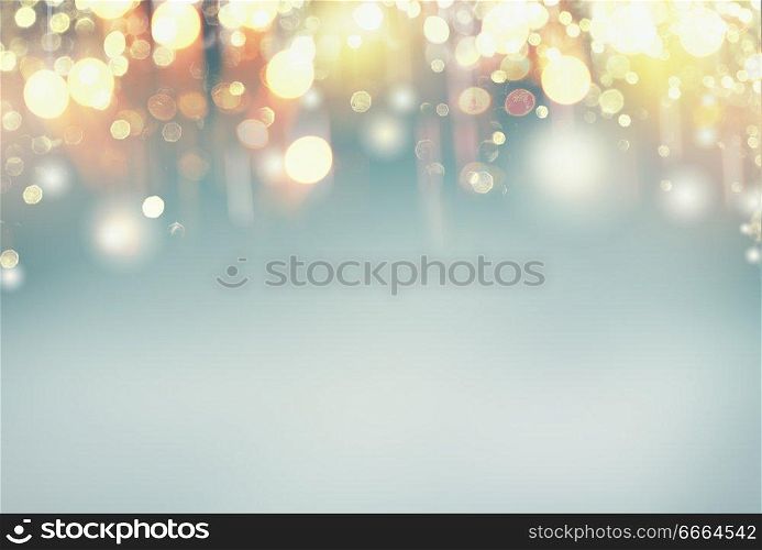 Festive holidays lighting bokeh on pastel blue background, frame with copy space